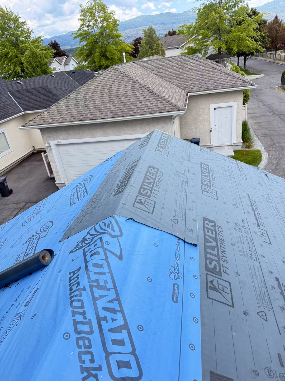 Synthetic underlayment exposed during multi-unit roofing work in Kelowna